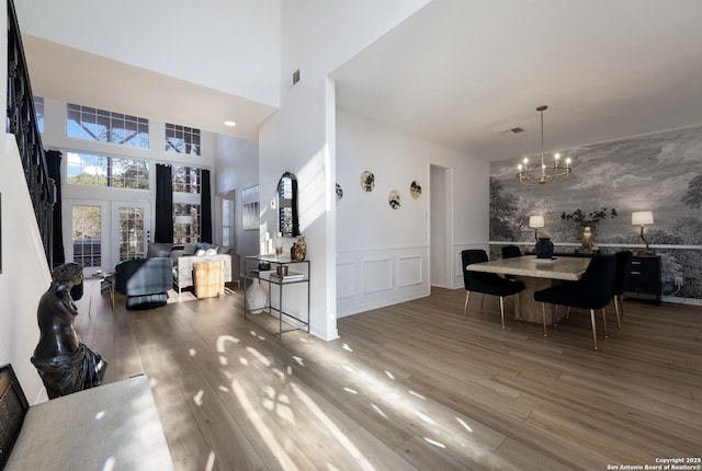 dining room featuring french doors, a towering ceiling, hardwood / wood-style flooring, and a notable chandelier