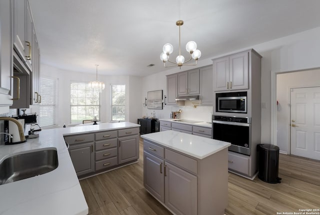 kitchen featuring gray cabinets, stainless steel appliances, an inviting chandelier, and sink