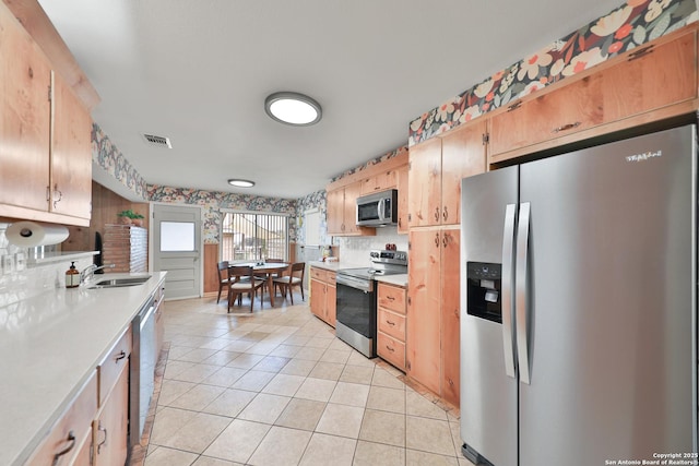 kitchen featuring backsplash, sink, light tile patterned floors, and stainless steel appliances