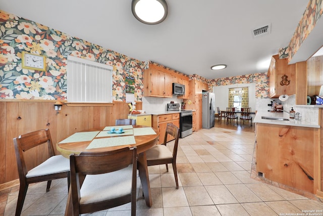 tiled dining room featuring wood walls and sink