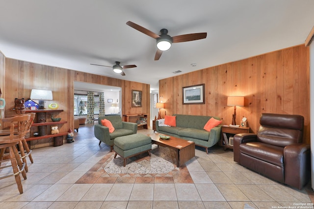 living room featuring wood walls, ceiling fan, and light tile patterned flooring