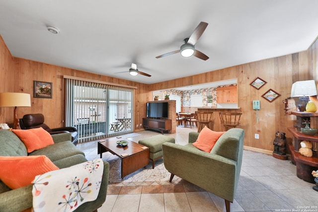 living room with light tile patterned floors, ceiling fan, and wood walls