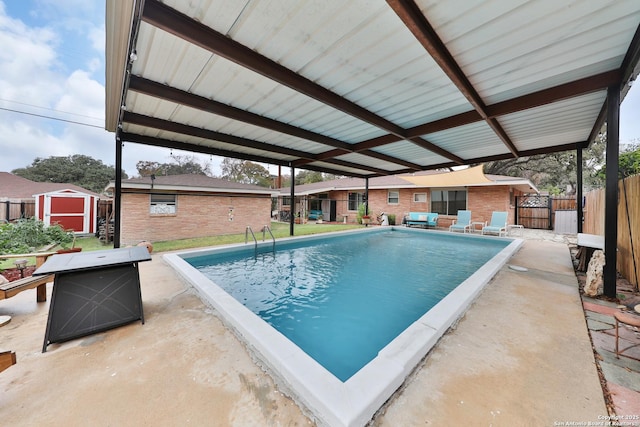 view of swimming pool with a patio, a fire pit, a storage shed, and a grill