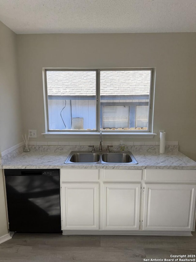 kitchen with white cabinets, a textured ceiling, black dishwasher, and sink