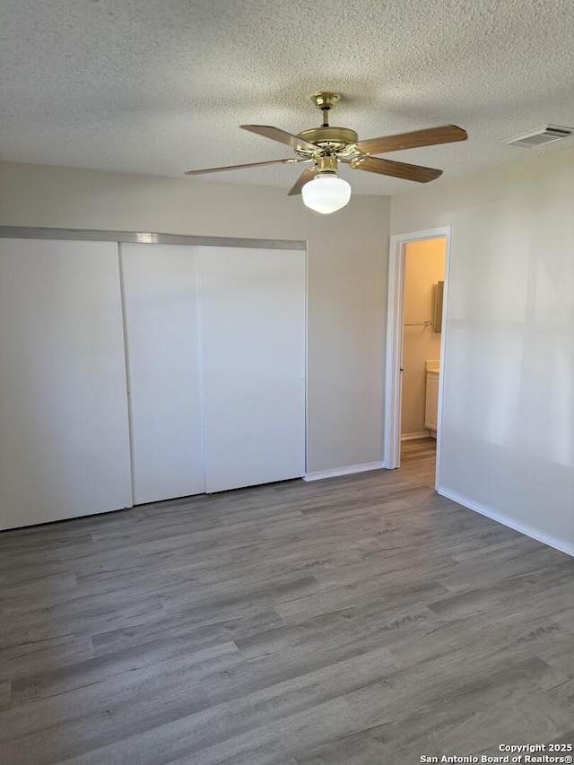 unfurnished bedroom with ceiling fan, a closet, and hardwood / wood-style flooring