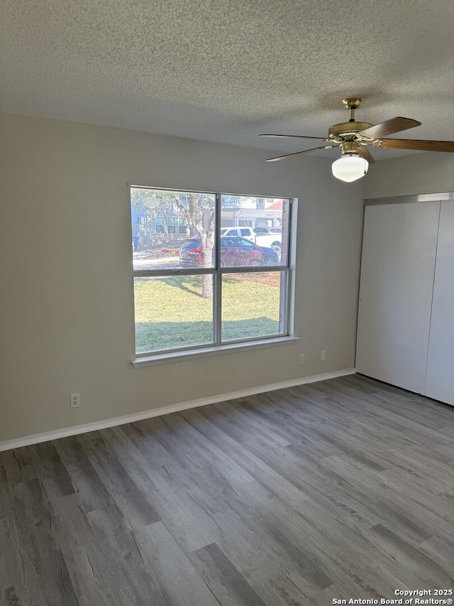 empty room with hardwood / wood-style floors, a textured ceiling, a wealth of natural light, and ceiling fan