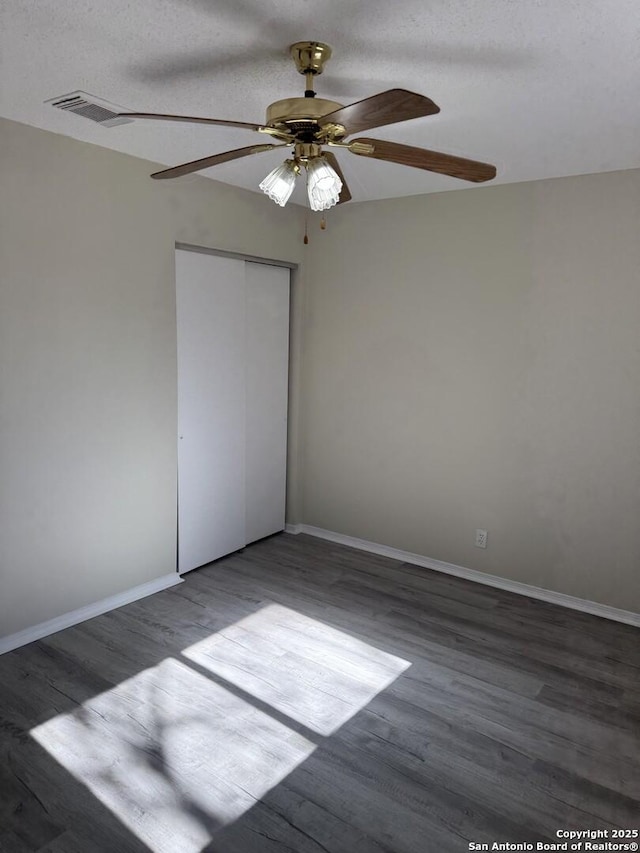 unfurnished bedroom featuring dark hardwood / wood-style flooring, ceiling fan, a closet, and a textured ceiling