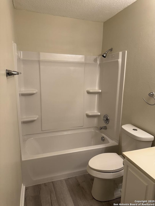 full bathroom with vanity, bathing tub / shower combination, hardwood / wood-style flooring, toilet, and a textured ceiling