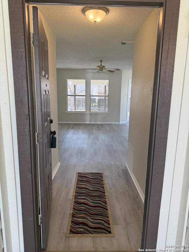 hallway featuring wood-type flooring and a textured ceiling