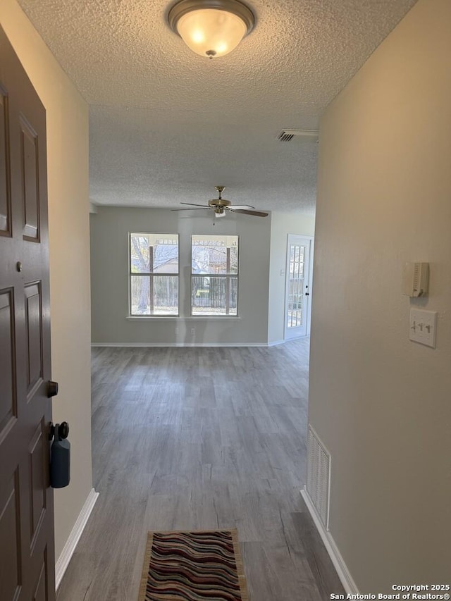 interior space with ceiling fan, wood-type flooring, and a textured ceiling