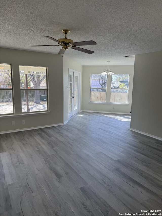 unfurnished living room featuring french doors, ceiling fan with notable chandelier, hardwood / wood-style floors, and a textured ceiling