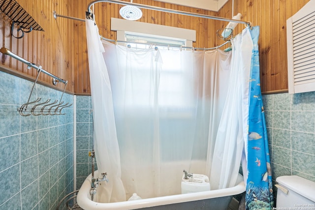 bathroom with toilet, tile walls, and shower / tub combo