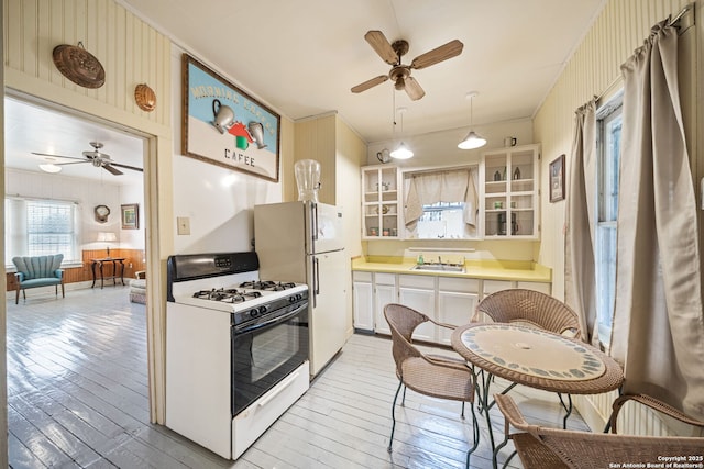 kitchen featuring sink, decorative light fixtures, white appliances, and light hardwood / wood-style floors