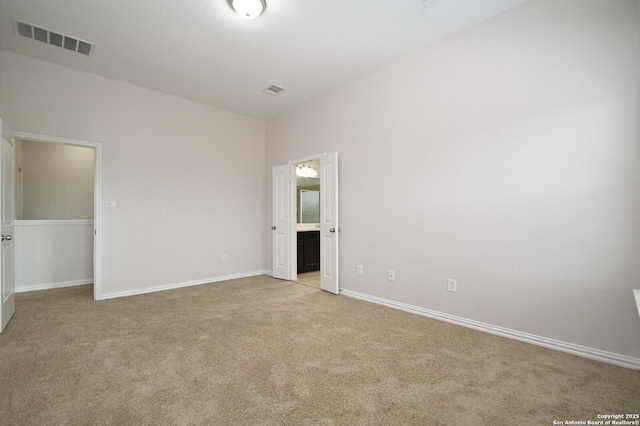 unfurnished bedroom featuring connected bathroom and light carpet