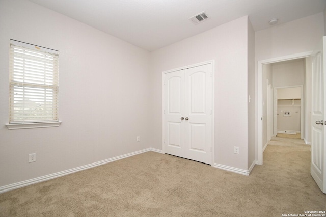 unfurnished bedroom featuring light carpet and a closet