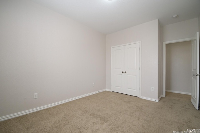 unfurnished bedroom featuring light carpet and a closet