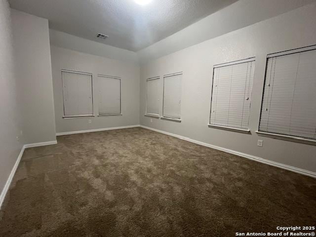 spare room featuring dark colored carpet and a textured ceiling