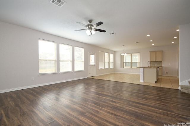 unfurnished living room with ceiling fan with notable chandelier, dark hardwood / wood-style floors, and sink