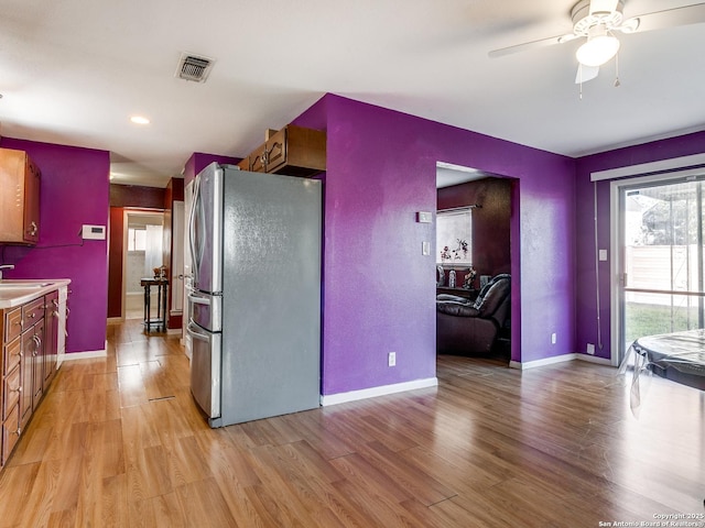 kitchen with light wood-type flooring, stainless steel refrigerator, ceiling fan, and sink