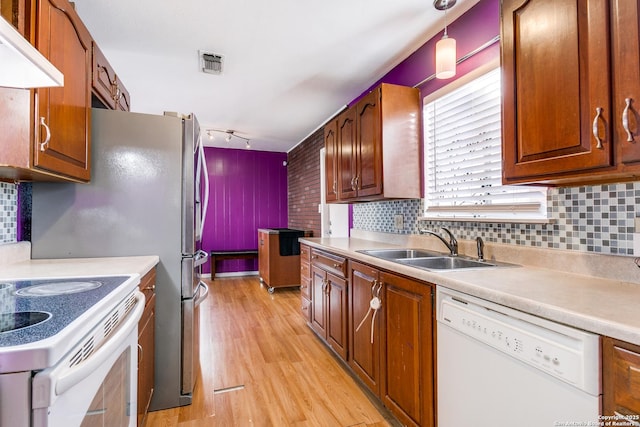 kitchen featuring white appliances, backsplash, sink, light wood-type flooring, and range hood