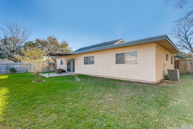 rear view of property with a lawn, cooling unit, and a patio