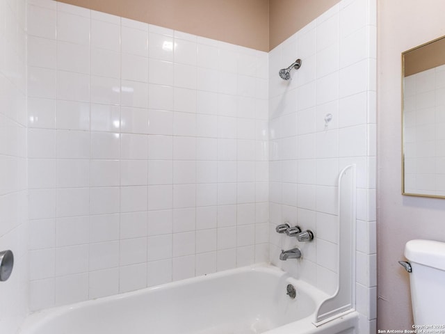 bathroom with tiled shower / bath combo and toilet