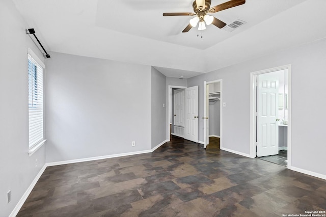 unfurnished bedroom featuring ceiling fan, a walk in closet, ensuite bathroom, and a closet