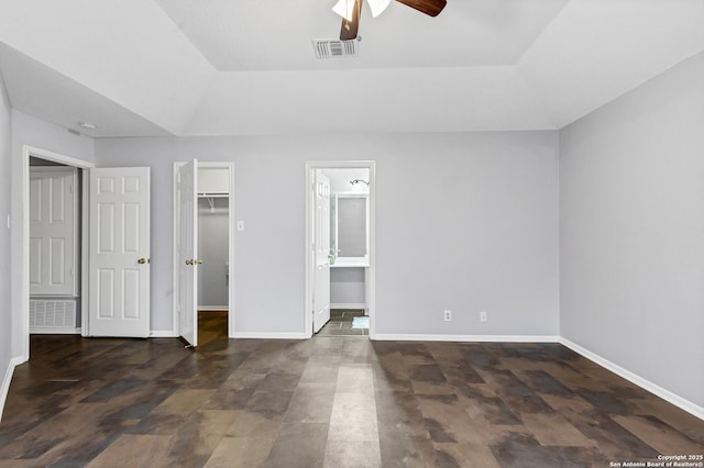 unfurnished bedroom featuring ceiling fan, a walk in closet, connected bathroom, and a closet