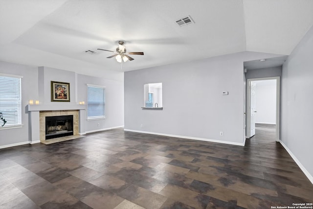 unfurnished living room featuring ceiling fan and a tile fireplace