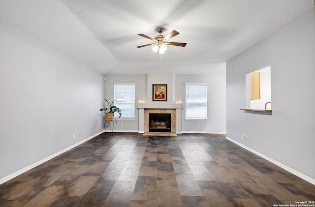 unfurnished living room with ceiling fan, a fireplace, and a textured ceiling