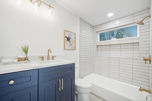 full bathroom featuring vanity, tiled shower / bath combo, and toilet