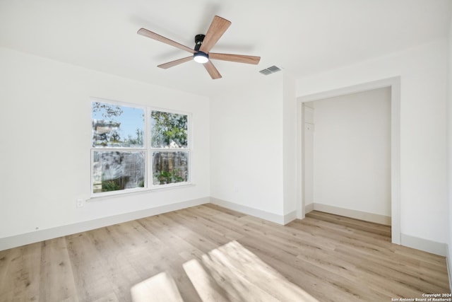 empty room with ceiling fan and light hardwood / wood-style flooring