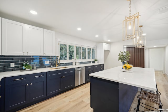 kitchen with sink, a center island, hanging light fixtures, stainless steel dishwasher, and white cabinets