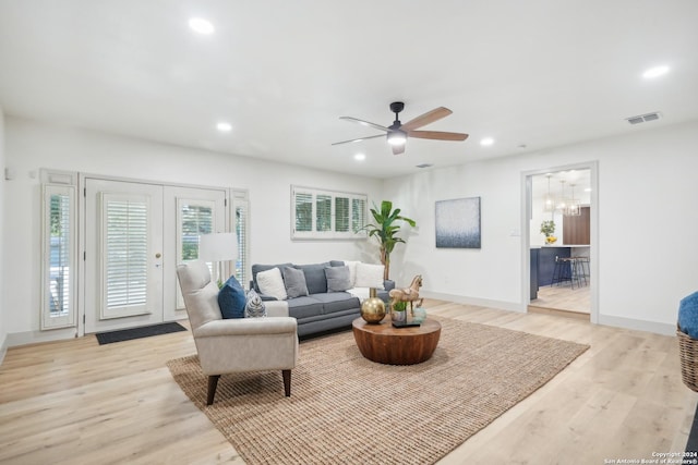 living room featuring light hardwood / wood-style flooring and ceiling fan with notable chandelier