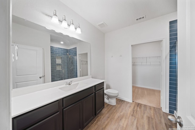 bathroom featuring hardwood / wood-style flooring, toilet, vanity, and walk in shower