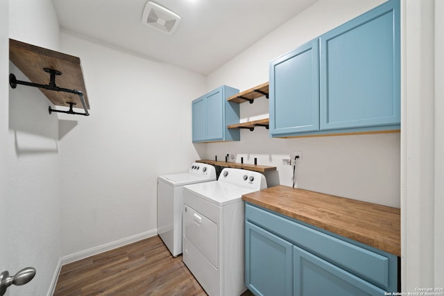 clothes washing area with dark hardwood / wood-style floors, cabinets, and washing machine and clothes dryer