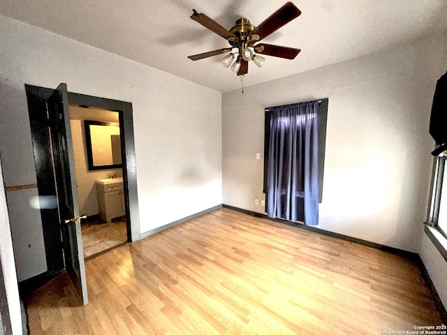 unfurnished bedroom featuring ensuite bathroom, ceiling fan, and light wood-type flooring