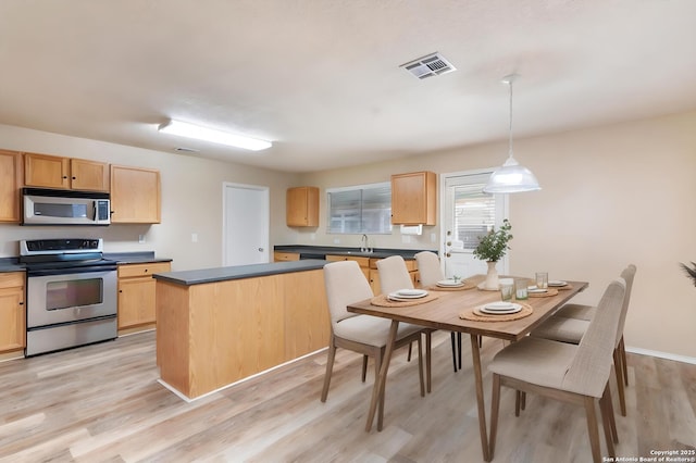 kitchen featuring pendant lighting, light wood-type flooring, light brown cabinetry, and electric stove