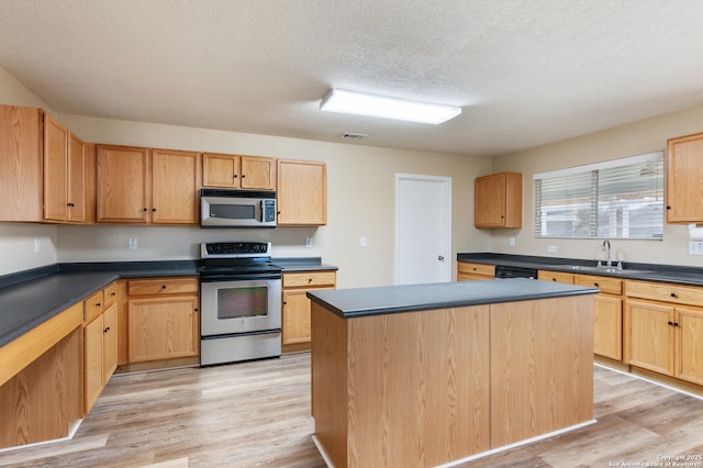 kitchen featuring appliances with stainless steel finishes, a textured ceiling, sink, light hardwood / wood-style flooring, and a center island