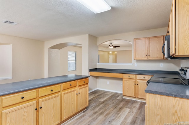 kitchen featuring ceiling fan, range with electric stovetop, built in desk, a textured ceiling, and light brown cabinetry