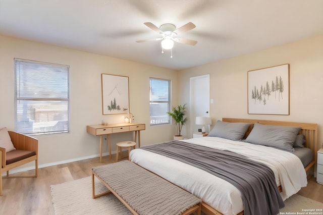 bedroom featuring ceiling fan, multiple windows, and light hardwood / wood-style flooring