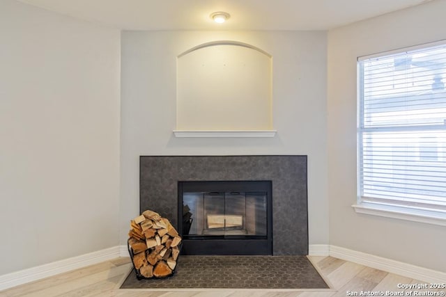 details with a tiled fireplace and hardwood / wood-style floors