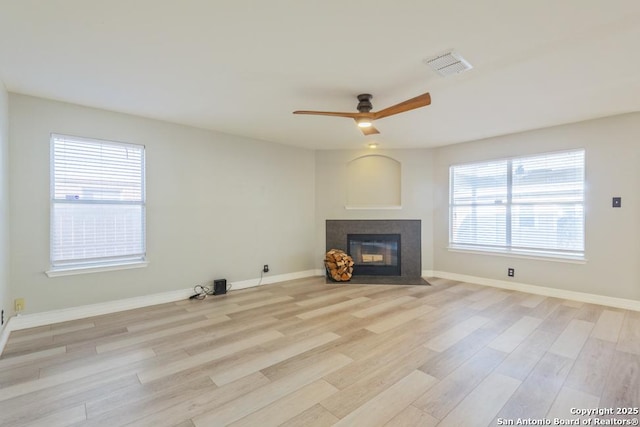 unfurnished living room featuring light hardwood / wood-style floors, ceiling fan, and a healthy amount of sunlight