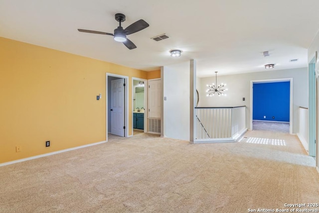 empty room with ceiling fan with notable chandelier and light colored carpet