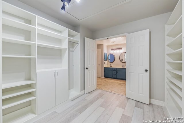 spacious closet with light hardwood / wood-style floors and sink