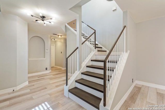 stairway with hardwood / wood-style floors and a chandelier