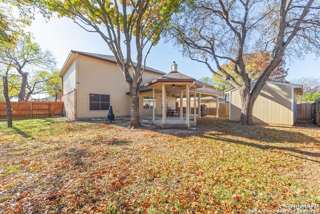 rear view of house featuring a storage unit, ceiling fan, a patio area, and a lawn