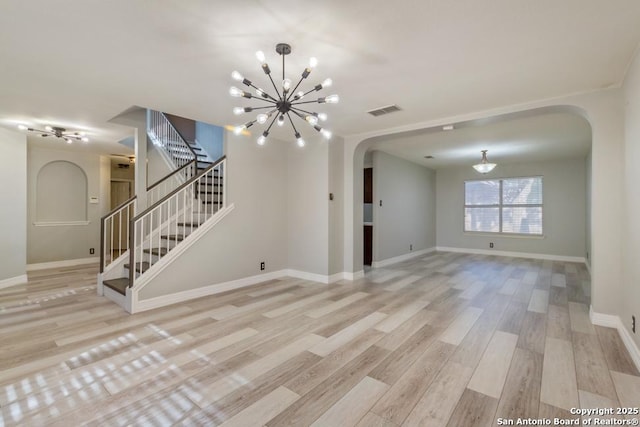 unfurnished living room featuring a chandelier and light hardwood / wood-style floors