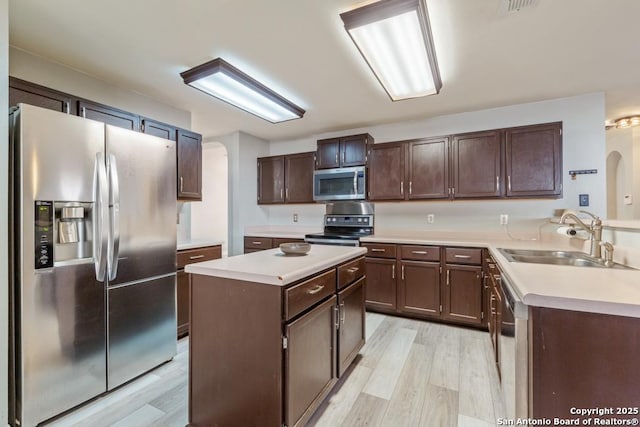 kitchen with dark brown cabinetry, stainless steel appliances, sink, light hardwood / wood-style flooring, and a center island