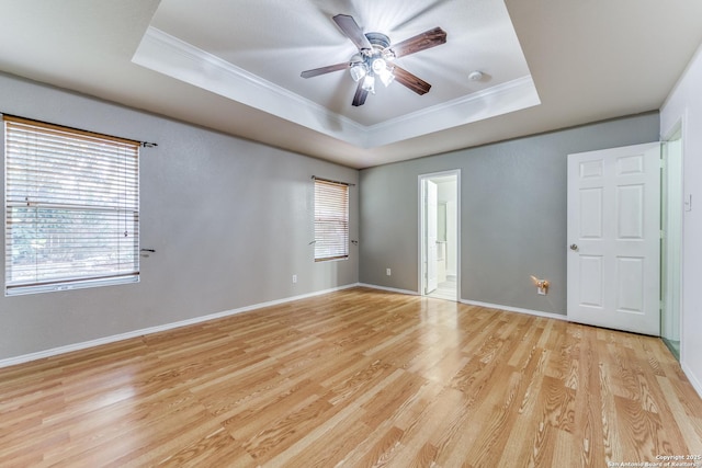 spare room with a tray ceiling, crown molding, ceiling fan, and light hardwood / wood-style floors